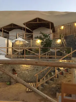 a resort in the middle of a desert with umbrellas at Ecocamp Huacachina in Ica