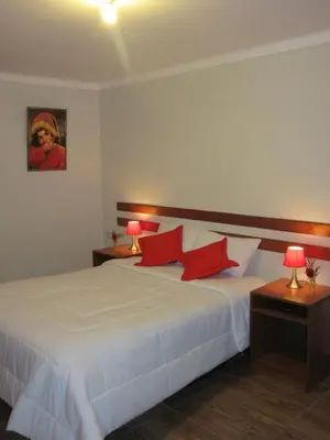 a bedroom with a white bed with red pillows at Cusco House in Cusco