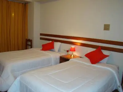 two beds with red pillows in a hotel room at Cusco House in Cusco