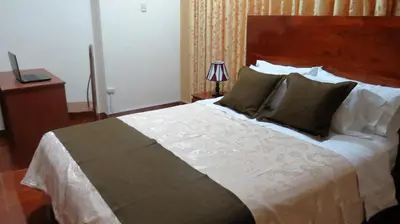 a bedroom with a large bed with a wooden headboard at Victtorios Hotel in Satipo