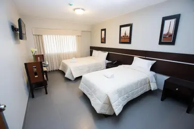 a hotel room with two beds with white sheets at Mariategui Hotel & Suites in Lima