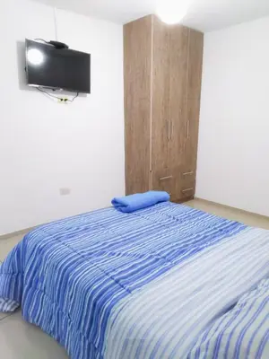 a bedroom with a bed with a tv on the wall at Departamento Monterrico in Lima