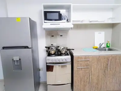 a small kitchen with a stove and a microwave at Departamento Monterrico in Lima