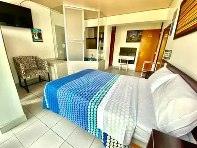 a bedroom with a blue and white bed and a chair at CasaHotel Jockey Plaza Mall in Lima
