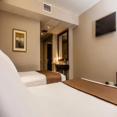 a hotel room with two beds and a flat screen tv at Del Pilar Miraflores Hotel in Lima