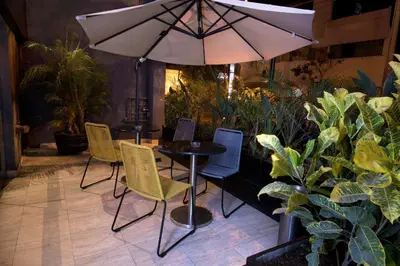 a table with chairs and an umbrella in a garden at Mariel Hotel Boutique in Lima