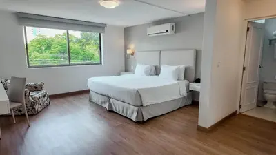 a bedroom with a large white bed and a window at El Golf Hotel Boutique in Lima