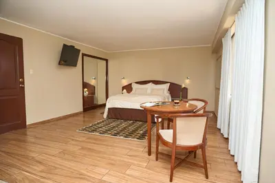a bedroom with a bed and a table and a desk at Hotel Park Suites in Lima