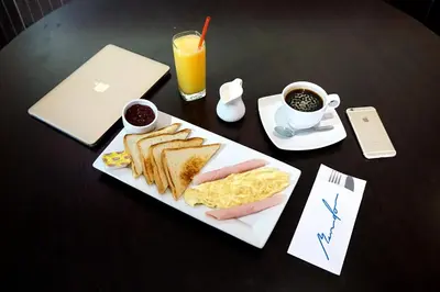 a table with a plate of breakfast food and a laptop at Gran Mundo Hotel & Suites in Lima