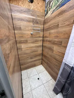 a bathroom with a shower with a wooden wall at Euler House`s in Cusco