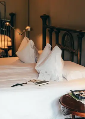 a bed with white pillows and a book on it at Atemporal by Andean in Lima