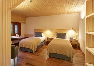 a bedroom with two beds and a table and a desk at Explora Valle Sagrado in Urubamba