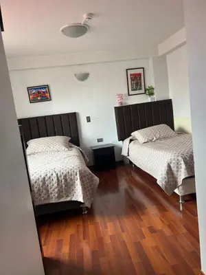 a bedroom with two beds and a wooden floor at Casa de Laura in Cusco