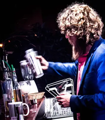 a man standing at a bar holding a drink at Waikiki Hostel in Lima