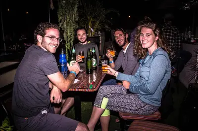 a group of people sitting around a table with drinks at Waikiki Hostel in Lima