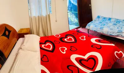 a bedroom with a red blanket with hearts on it at Ukumari Hostel in Cusco
