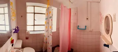 a bathroom with a shower with a toilet and a window at Ukumari Hostel in Cusco