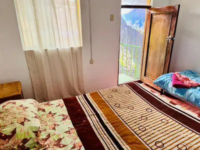 a bedroom with a bed and a large window at Ukumari Hostel in Cusco