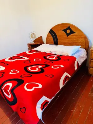 a bed with a red and white comforter with hearts on it at Ukumari Hostel in Cusco