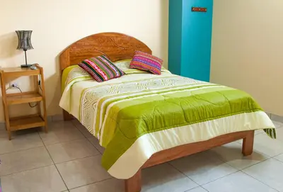 a bed with a green blanket and pillows on it at B&B Valcava in Urubamba