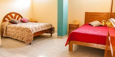 a bedroom with two beds and a red blanket at B&B Valcava in Urubamba