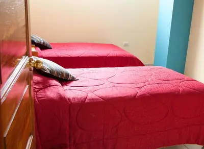 a bedroom with two beds with red sheets and pillows at B&B Valcava in Urubamba