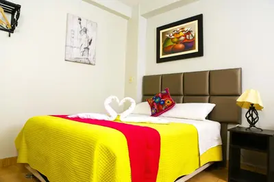 a bedroom with a bed with a yellow and red blanket at Hostal Mica in Abancay