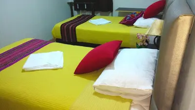 two beds with yellow and red pillows in a room at Hostal Mica in Abancay