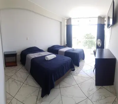 a hotel room with two beds and a window at Regency Plaza Hotel in Pisco