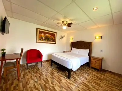 a bedroom with a bed and a desk and a chair at Hotel Resort Thiago in Chincha Alta