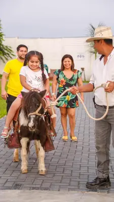 a young girl riding a pony with a boy at Hotel Resort Thiago in Chincha Alta