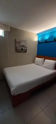 a bedroom with a large bed with a blue headboard at Residencial Alfa Hotel in Lima
