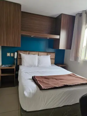 a bedroom with a large bed with a blue wall at Residencial Alfa Hotel in Lima