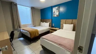 a hotel room with two beds and a window at Residencial Alfa Hotel in Lima