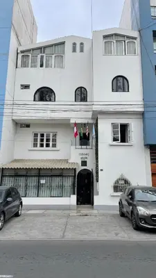 a white building with two cars parked in front of it at Residencial Alfa Hotel in Lima