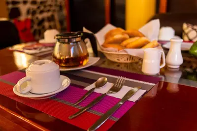 a table with a cup of tea and a basket of bread at Peru Quechua's Lodge Ollantaytambo in Ollantaytambo