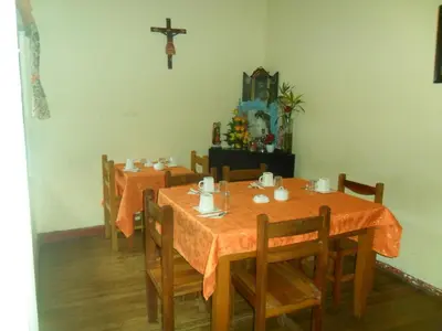 a dining room with two tables and a cross on the wall at Chaquill Chak'a in Cusco