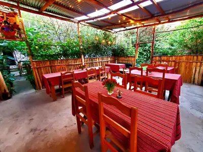 a restaurant with red tables and wooden chairs at Hospedaje K'uchuwasi in Ollantaytambo