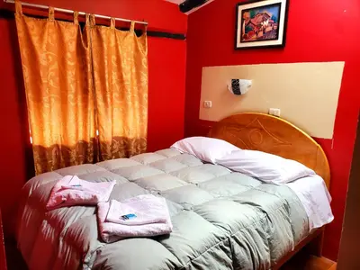 a bedroom with a bed with red walls at Hospedaje K'uchuwasi in Ollantaytambo