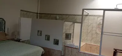 a bedroom with a shower and a bed and a mirror at Motel Sahara Suites in Barranca