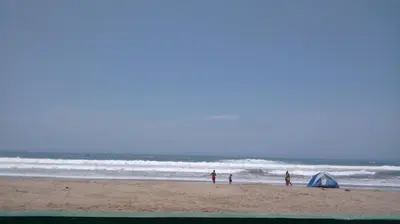 a group of people standing on a beach with a tent at Motel Sahara Suites in Barranca