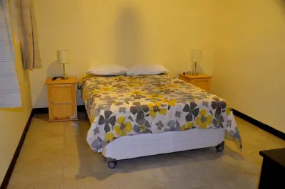 a bedroom with a bed and two night stands with lamps at Wild Olive Guest House in Ica
