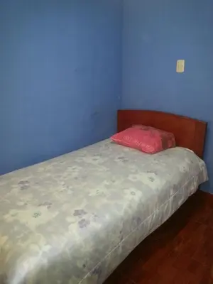 a small bed in a blue room with a red pillow at Hostal Arcangel in Abancay