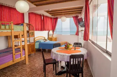 a room with two bunk beds and a table and chairs at Cruz del Sur in Pucusana