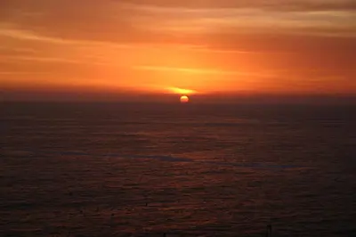 a sunset over the ocean with the sun in the sky at Cruz del Sur in Pucusana