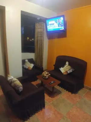 a living room with two couches and a tv at Starlight Inn in Pisco