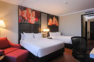 a hotel room with two beds and a red chair at Hilton Garden Inn Lima Surco in Lima