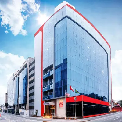 a tall glass building with a red roof at Hilton Garden Inn Lima Surco in Lima