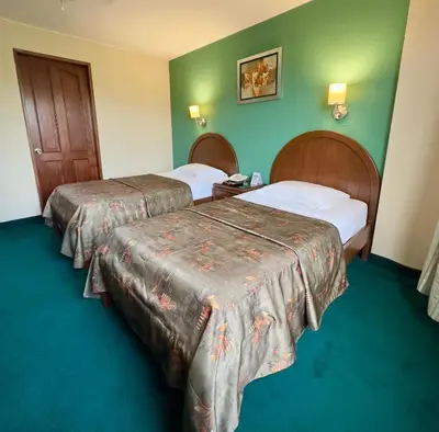 two beds in a hotel room with green walls at Hotel La Molina in Lima
