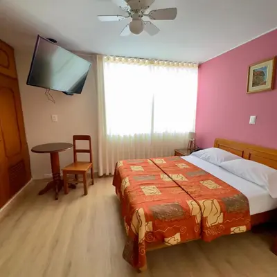 a bedroom with a bed and a flat screen tv at Hotel La Molina in Lima